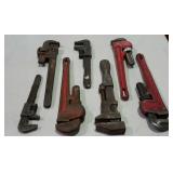 Seven pipe wrenches, assorted brands and sizes.