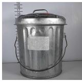 Small galvanized trashcan with handle and lid.