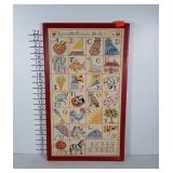 Alphabet needlepoint sampler in red wooden frame.
