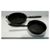 Two well seasoned, iron frying pans with wood