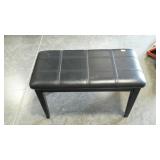 Piano bench with a few piano related items.