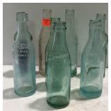 Eight  soda bottles one is flat sided Coca-Cola