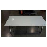Adjustable white glass top table. Twist and pull