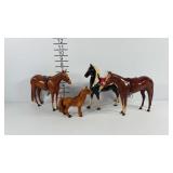 Four toy horses. One with fur, three plastic, all