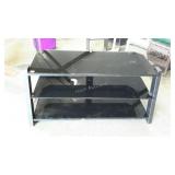 Three tiered, glass shelf entertainment center.