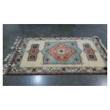 Wool area rug with braided fringe on one end.