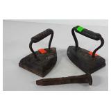 Two cast iron sad irons and one railroad spike,