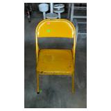 Metal folding chair with flaking yellow paint,