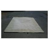 Tan wool area rug, measures 134 inches long by 97