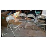 Four metal folding chairs with attached desktops.