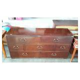 Long, seven drawer dresser with brass accents.