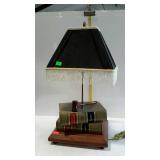 Table lamp with fringed cloth shade, stacked  book