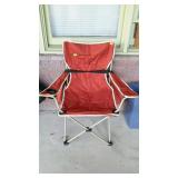 Red folding camping chair with bag, located on