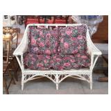 Wicker love seat with flowered cushions. Some