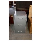 Three drawer metal file cabinet has key gray