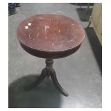 Round wooden table on tri footed base, top does