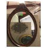 Oval mirror with carved basket design on top of