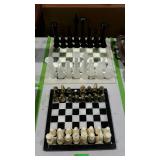 Two marble chess sets. Each has a broken piece or
