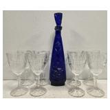 8 clear glasses and blue decanter