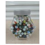 Glass jar full of marbles and shooters