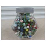 Glass jar full of assorted marbles and shooters