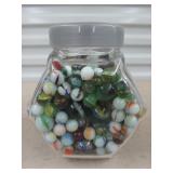 Glass jar full of assorted marbles and shooters