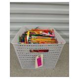 Plastic tub full of colored pencils, markers,