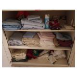 Three shelves of linens/bathroom supplies,