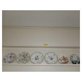 Top shelf of trinkets, all pretty plates, one is