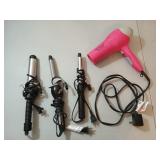Three curling irons and a pink hair dryer, all