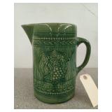 Green pottery pitcher with barrel / grape motif,