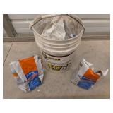 5 gallon bucket filled with open bags of grout,