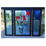 Three panels of stained glass window, hanging in
