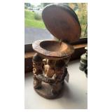 Five carved wood people standing in a circle all