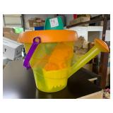 Plastic watering can full of beach, sand toys
