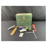 Green metal box with various items including