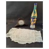 Decorative bottle, mantle clock, and doilies