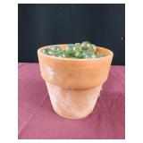 Clay flower pot full of green glass balls