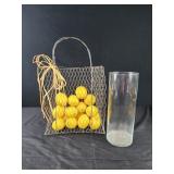 Faux lemons in wire bag, tall glass vase