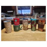 Assorted travel tumblers and Starbucks mug