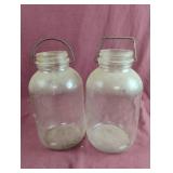 2 half gallon glass jugs with metal handles