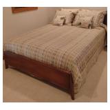 Vintage wood bed with comforter and shams.