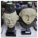 Two contemporary carved faces on pedestal
