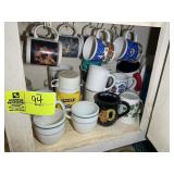 BOTTOM SHELF WITH ASSORTED COFFEE MUGS, PLATES, TH