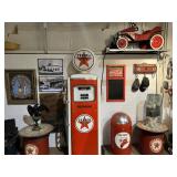 Restored Texaco gas pump surrounded by period advertising, oil cans, signage, and service station co