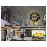 Wall display of vintage road signs, neon advertising, and gas & oil service signage