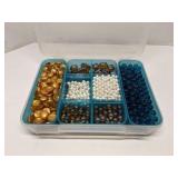 Group of decorative glass beads in storage bin