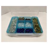 Group of decorative glass beads in storage bin
