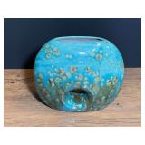 Turquoise and brown reactive glaze ceramic donut-shaped vase with a central cutout hole.