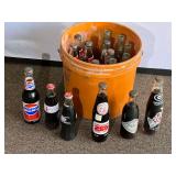 Garage… Bucket of assorted commemorative Pepsi and Coca-Colas, also includes vintage empty Coca-Cola glass bottles. See pictures for details.